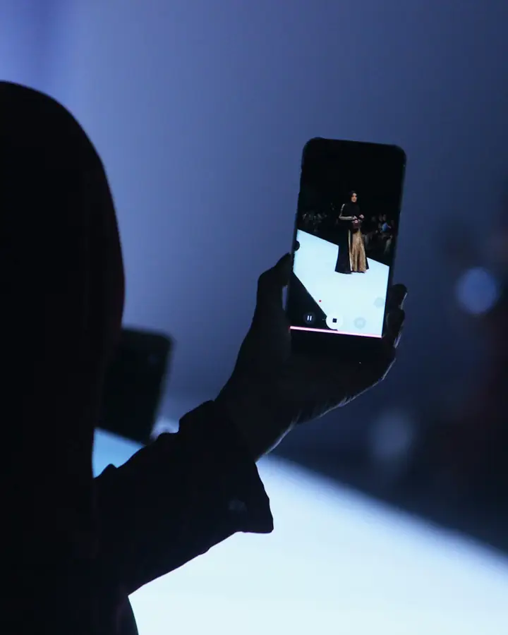 A person in Jakarta recording a fashion show on a phone